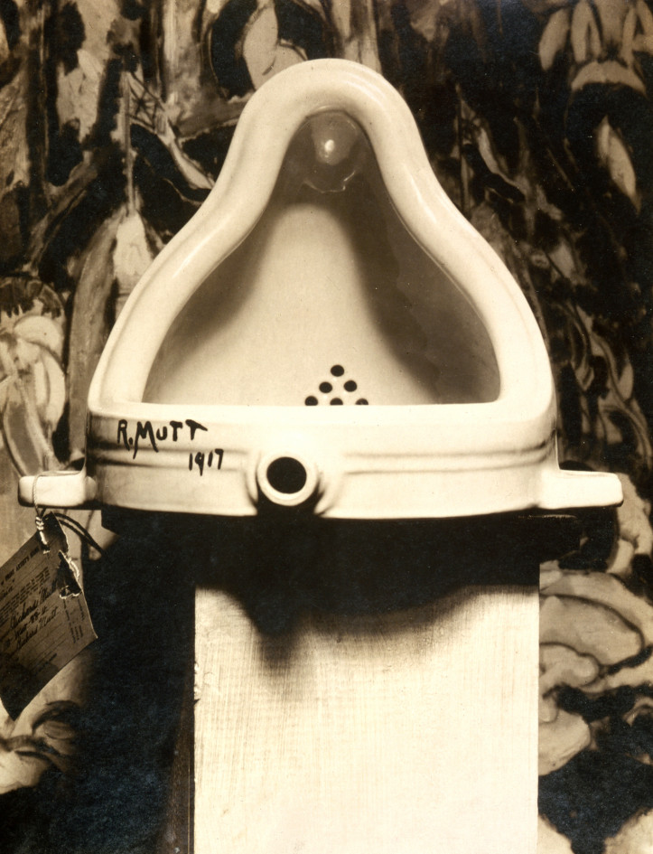 Marcel Duchamp, „Fontanna”, 1917 r., sfotografowana przez A.Stieglitza w galerii sztuki 291, w tle obraz Wojownicy (The Warriors) Marsdena Hartleya, źródło: domena publiczna